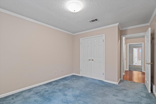 unfurnished bedroom with carpet, visible vents, baseboards, and a textured ceiling