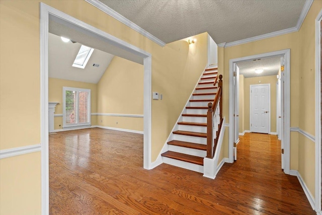 stairway featuring a textured ceiling, wood finished floors, and baseboards