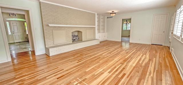 unfurnished living room featuring built in features, crown molding, visible vents, baseboards, and wood finished floors