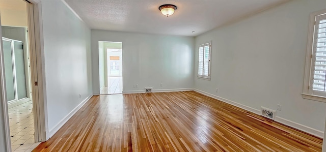 empty room featuring baseboards, visible vents, and light wood-style flooring