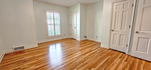 unfurnished bedroom with ornamental molding, light wood finished floors, visible vents, and baseboards