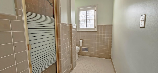 bathroom featuring visible vents, a stall shower, toilet, tile walls, and tile patterned floors
