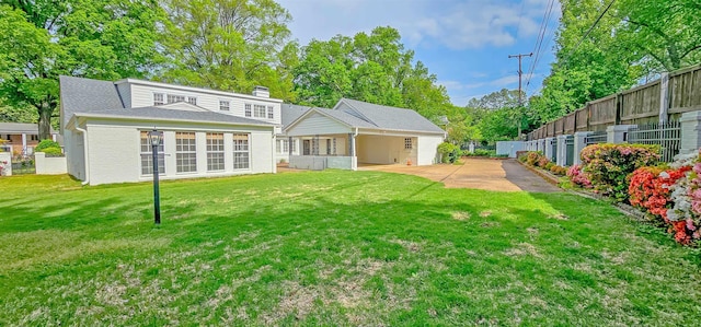 rear view of property with a chimney, fence, a shingled roof, a patio area, and a lawn