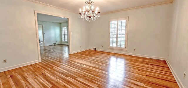 empty room featuring ornamental molding, an inviting chandelier, baseboards, and light wood-type flooring