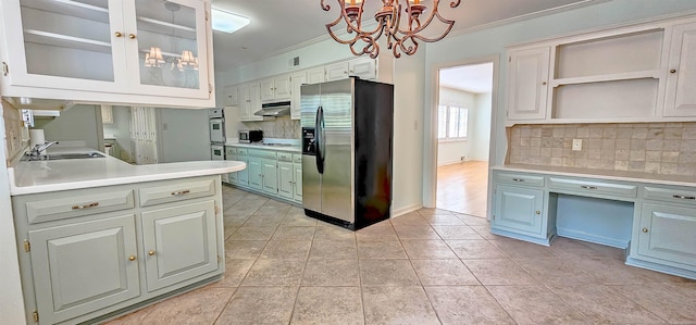 kitchen featuring under cabinet range hood, stainless steel refrigerator with ice dispenser, ornamental molding, and a sink