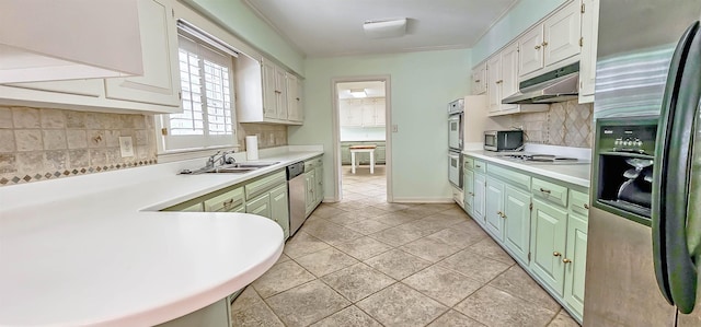 kitchen with a sink, stainless steel appliances, under cabinet range hood, tasteful backsplash, and light countertops