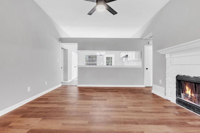 2568 Parkview Dr, Memphis, TN 38128 - unfurnished living room with visible vents, a stone fireplace, baseboards, wood finished floors, and ceiling fan with notable chandelier