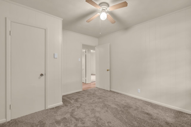 unfurnished bedroom featuring baseboards, a ceiling fan, crown molding, and carpet
