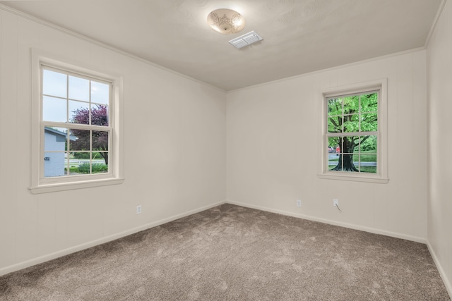 carpeted spare room featuring crown molding, visible vents, and baseboards