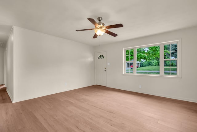 spare room featuring a ceiling fan, light wood-style flooring, and baseboards