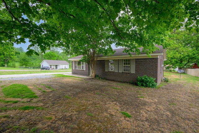 ranch-style home featuring fence and brick siding