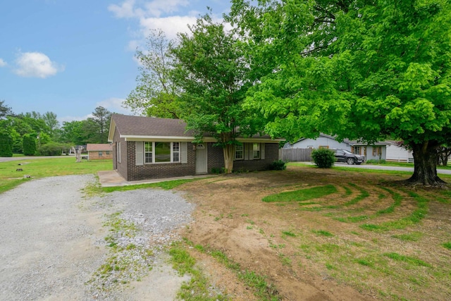 view of front of house with brick siding, fence, and driveway