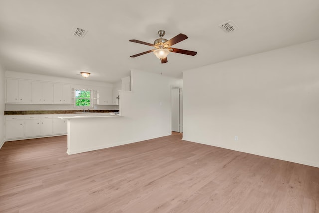 unfurnished living room with a ceiling fan, visible vents, and light wood-style floors
