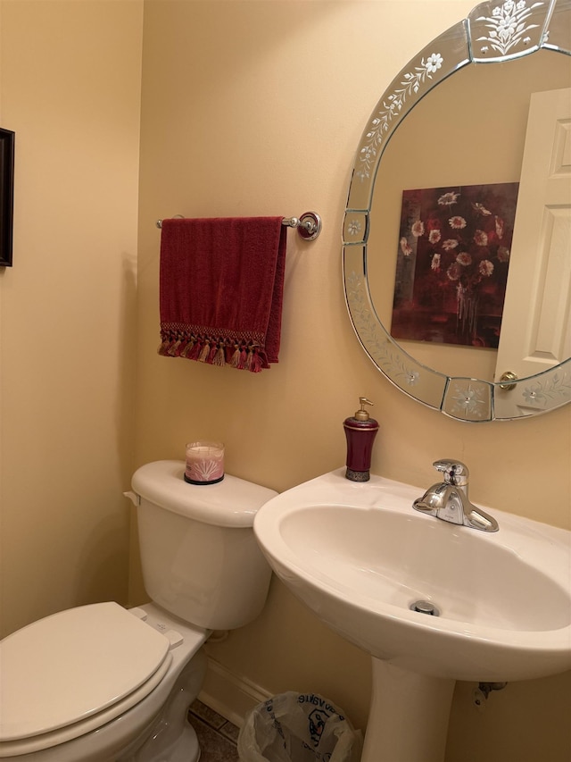 bathroom with toilet, a sink, and tile patterned floors