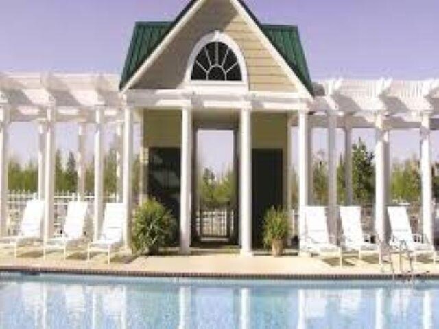 community pool with an outdoor structure, a pergola, and an exterior structure