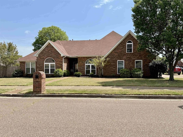traditional-style home featuring brick siding, a front lawn, and roof with shingles