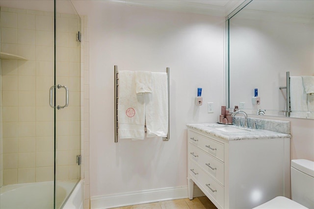 bathroom featuring combined bath / shower with glass door, baseboards, toilet, ornamental molding, and vanity