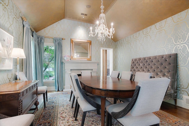 dining room with wood finished floors, an inviting chandelier, wallpapered walls, vaulted ceiling, and visible vents