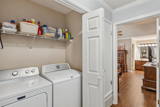washroom with ornamental molding, hardwood / wood-style flooring, laundry area, and washing machine and dryer