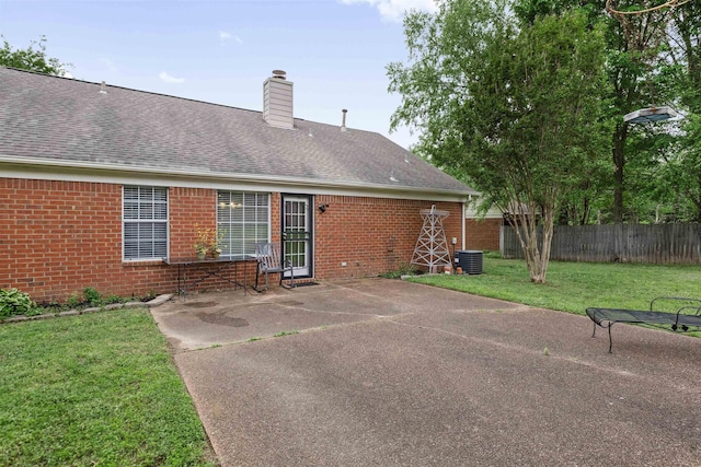 rear view of property featuring a patio area, central air condition unit, fence, a yard, and brick siding
