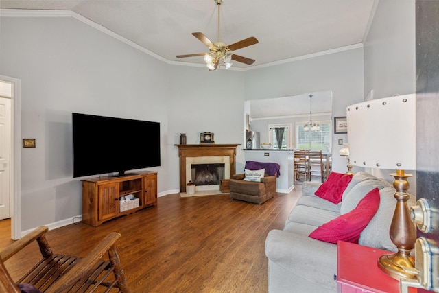 living room featuring ceiling fan, baseboards, ornamental molding, vaulted ceiling, and wood finished floors