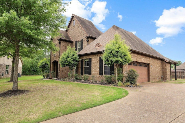 view of front facade featuring brick siding, a garage, driveway, roof with shingles, and a front lawn