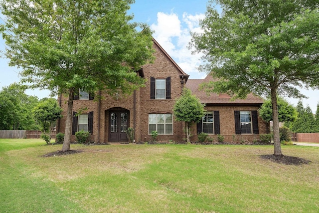 traditional-style house featuring brick siding, fence, and a front lawn