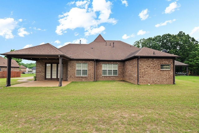 rear view of property featuring a patio, brick siding, roof with shingles, and a lawn