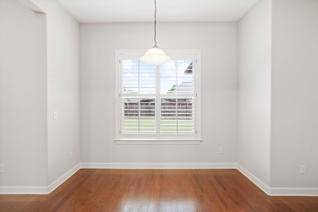 unfurnished dining area with wood finished floors and baseboards