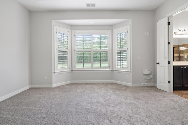 spare room featuring baseboards, visible vents, and carpet floors