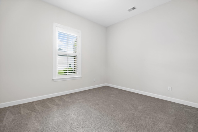 unfurnished room featuring visible vents, dark colored carpet, and baseboards