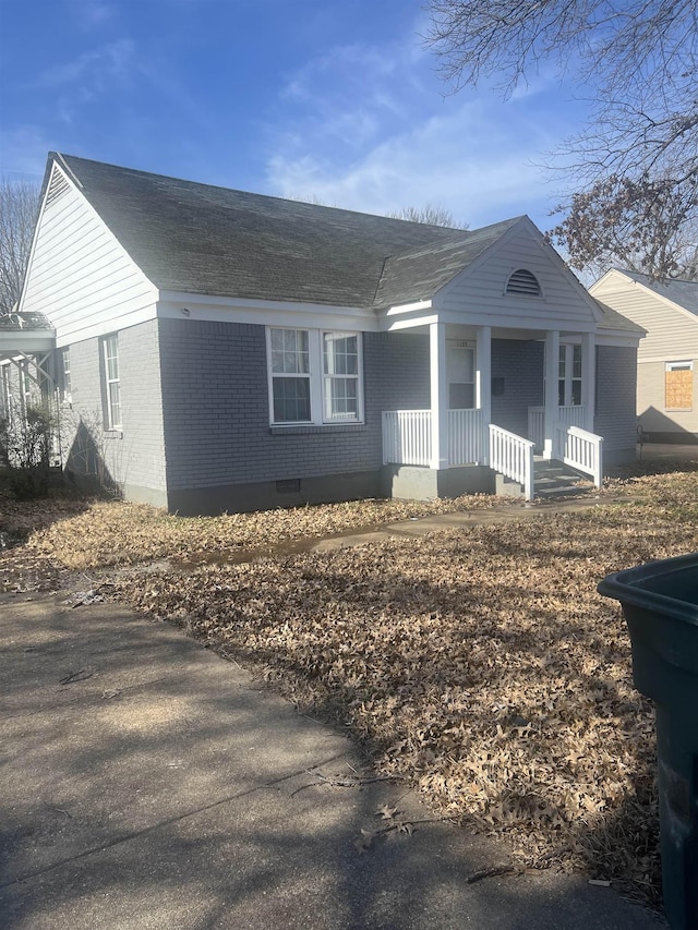 view of front of property with roof with shingles, crawl space, covered porch, and brick siding