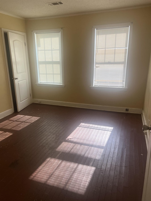 spare room with visible vents, hardwood / wood-style floors, ornamental molding, and baseboards