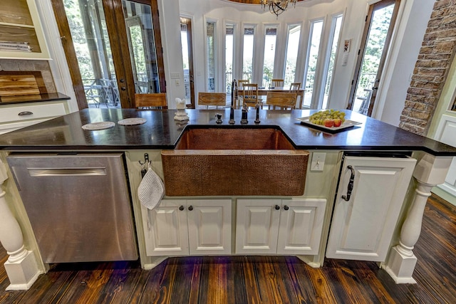 kitchen featuring dark countertops, plenty of natural light, dishwasher, and a sink
