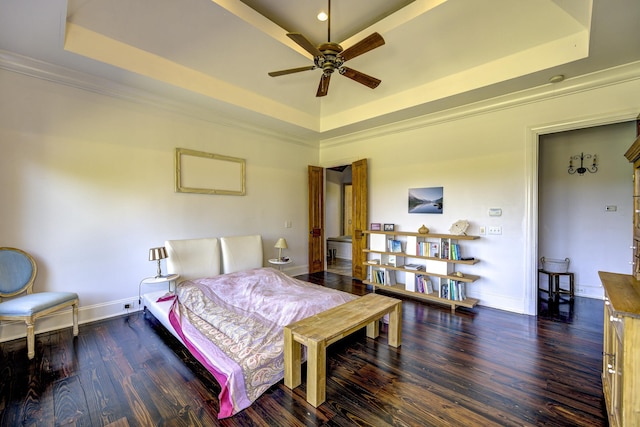 bedroom with baseboards, wood finished floors, and a tray ceiling