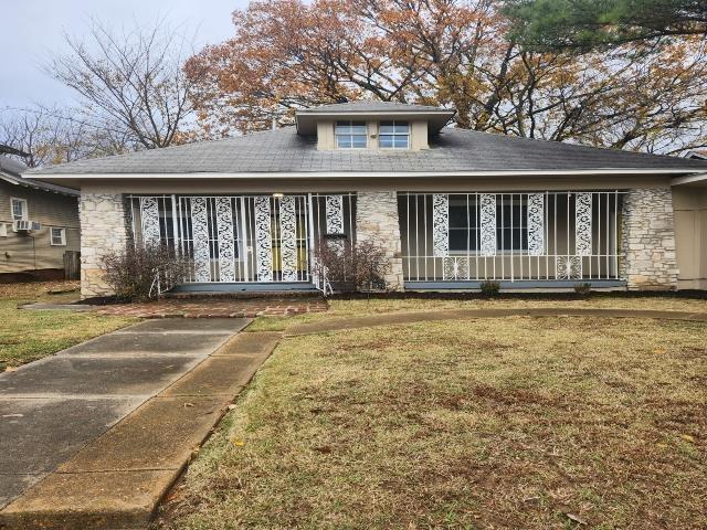 view of front facade featuring a porch, a front lawn, and stone siding