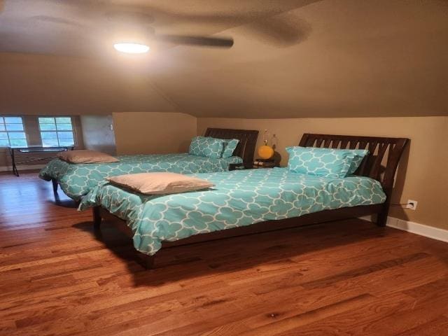 bedroom featuring wood finished floors, ceiling fan, vaulted ceiling, and baseboards
