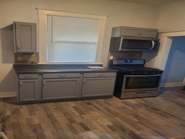 kitchen featuring appliances with stainless steel finishes, dark wood-style flooring, dark countertops, and gray cabinets