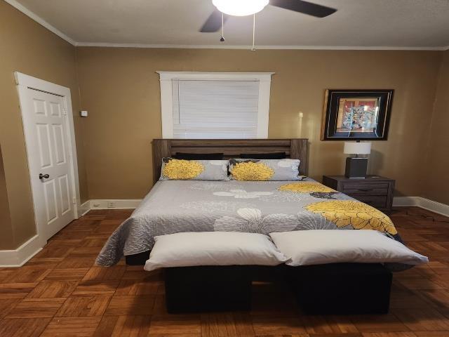 bedroom with a ceiling fan, ornamental molding, and baseboards