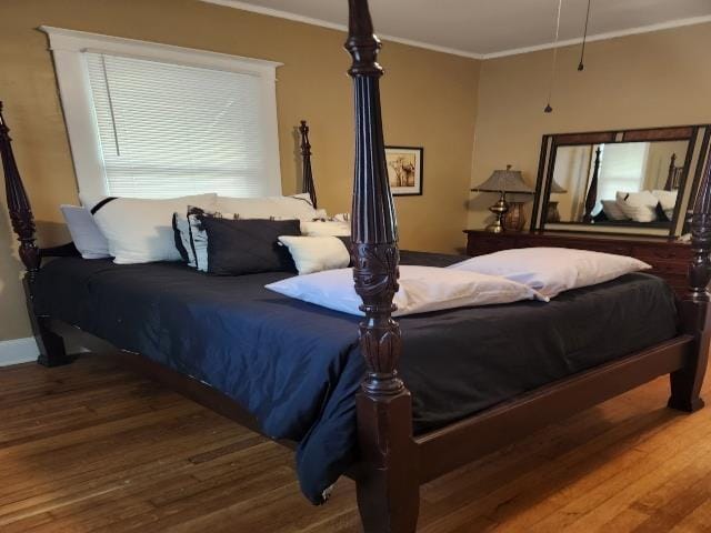 bedroom featuring crown molding, wood finished floors, and baseboards
