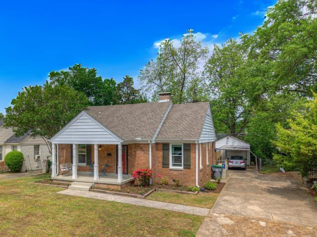 3704 Charleswood Ave, Memphis, TN 38122 - bungalow-style house featuring a porch, brick siding, a carport, a front lawn, and a chimney