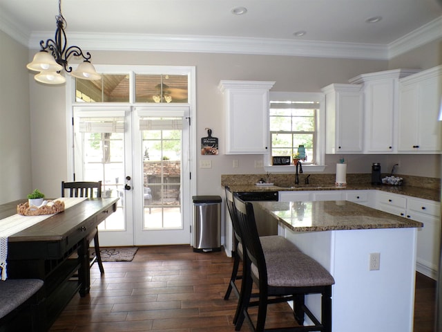 kitchen featuring an inviting chandelier, a kitchen island, dark wood-style flooring, a sink, and white cabinetry