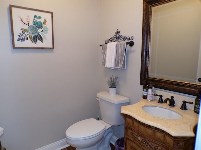 bathroom with toilet, vanity, and baseboards