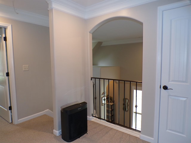 hallway featuring ornamental molding, arched walkways, carpet floors, and baseboards