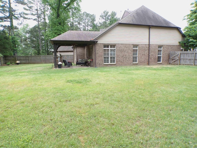 rear view of house featuring brick siding, a fenced backyard, and a yard