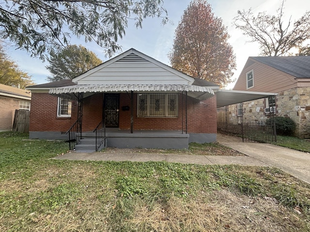 bungalow-style home with fence, a front lawn, brick siding, a carport, and driveway