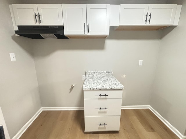 clothes washing area with baseboards and light wood-style flooring