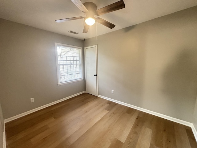 empty room with ceiling fan, baseboards, visible vents, and wood finished floors