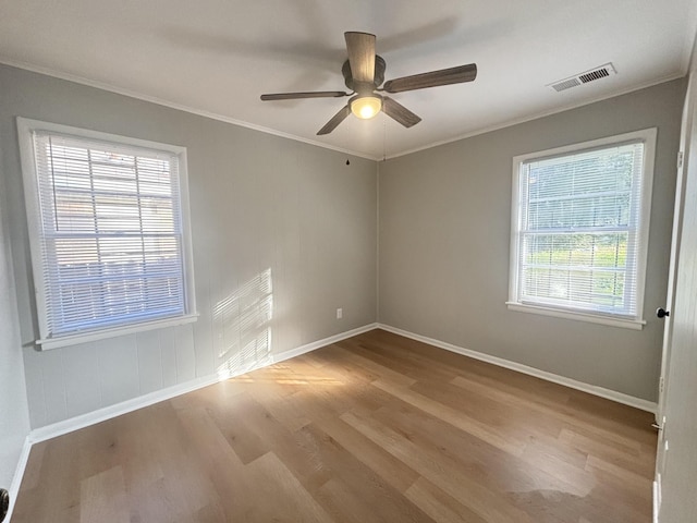 empty room with visible vents, baseboards, crown molding, and wood finished floors