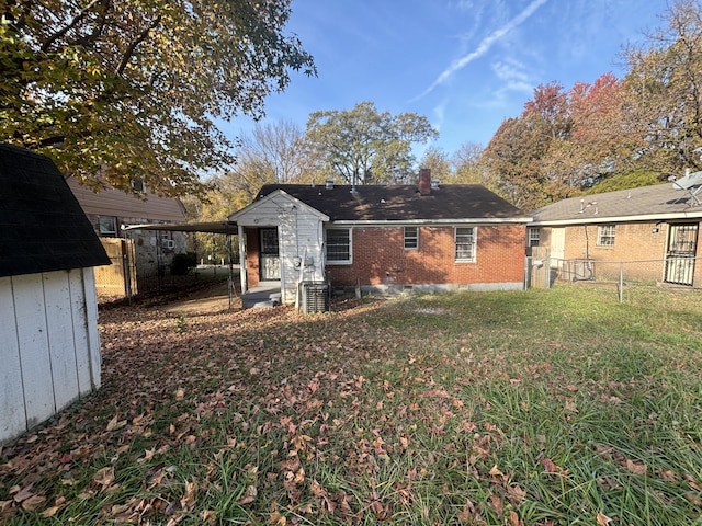 back of property featuring fence, a chimney, brick siding, a storage unit, and a yard